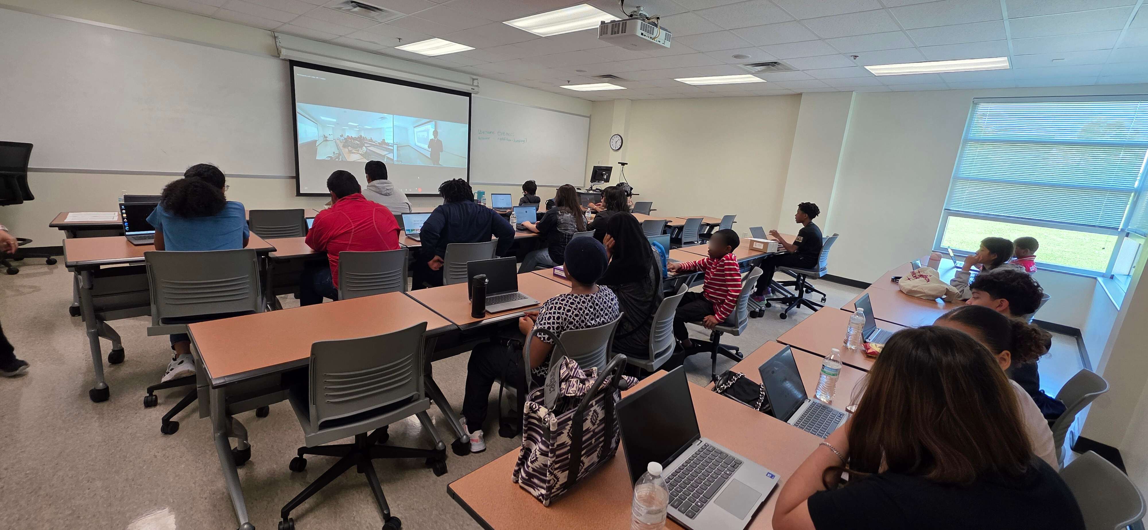 Students attending workshop at Houston Community College Codefest with laptops and projector screen